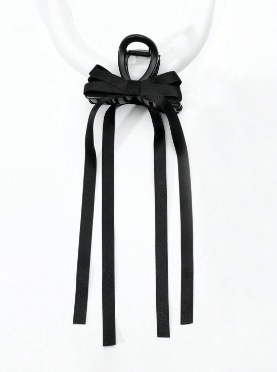 Svart satins hårklämma med rosett och långa band i flickas hår