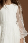 Närbild på transparenta tyllärmar och markerad midja på cremevit flickklänning Holly